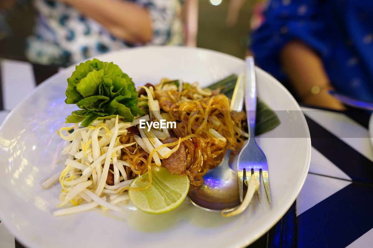 food, food and drink, lunch, meal, plate, freshness, healthy eating, pasta, dish, restaurant, wellbeing, table, thai food, business, italian food, cuisine, indoors, fast food, focus on foreground, close-up, supper, adult, eating utensil, spaghetti, vegetable, kitchen utensil, serving size, women, asian food