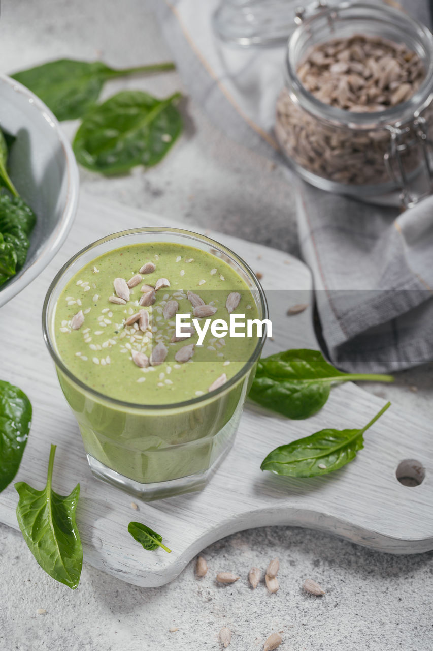 Glass of homemade healthy green smoothie with fresh baby spinach