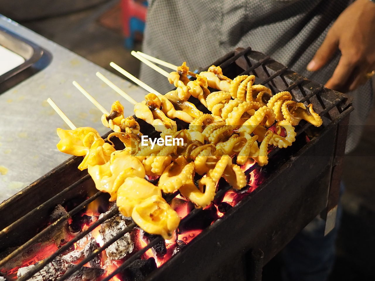 Close-up of person preparing food on barbecue grill