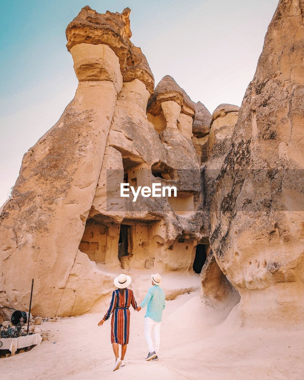 Rear view of couple holding hands while standing against rock formations