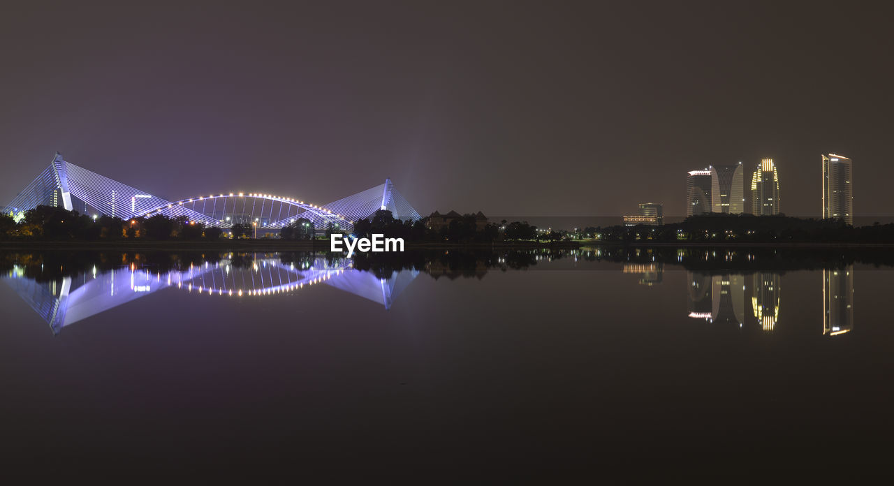 REFLECTION OF ILLUMINATED BUILDINGS IN RIVER AGAINST SKY