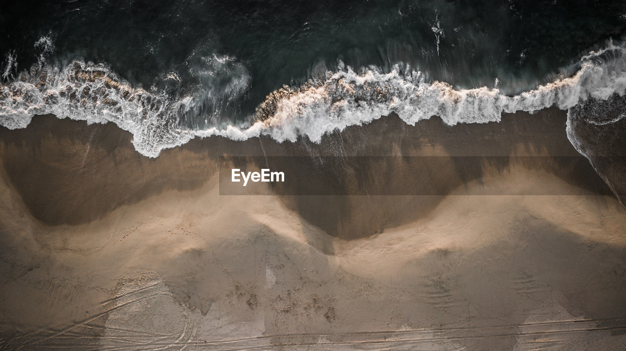 Aerial view of sea waves rushing at beach