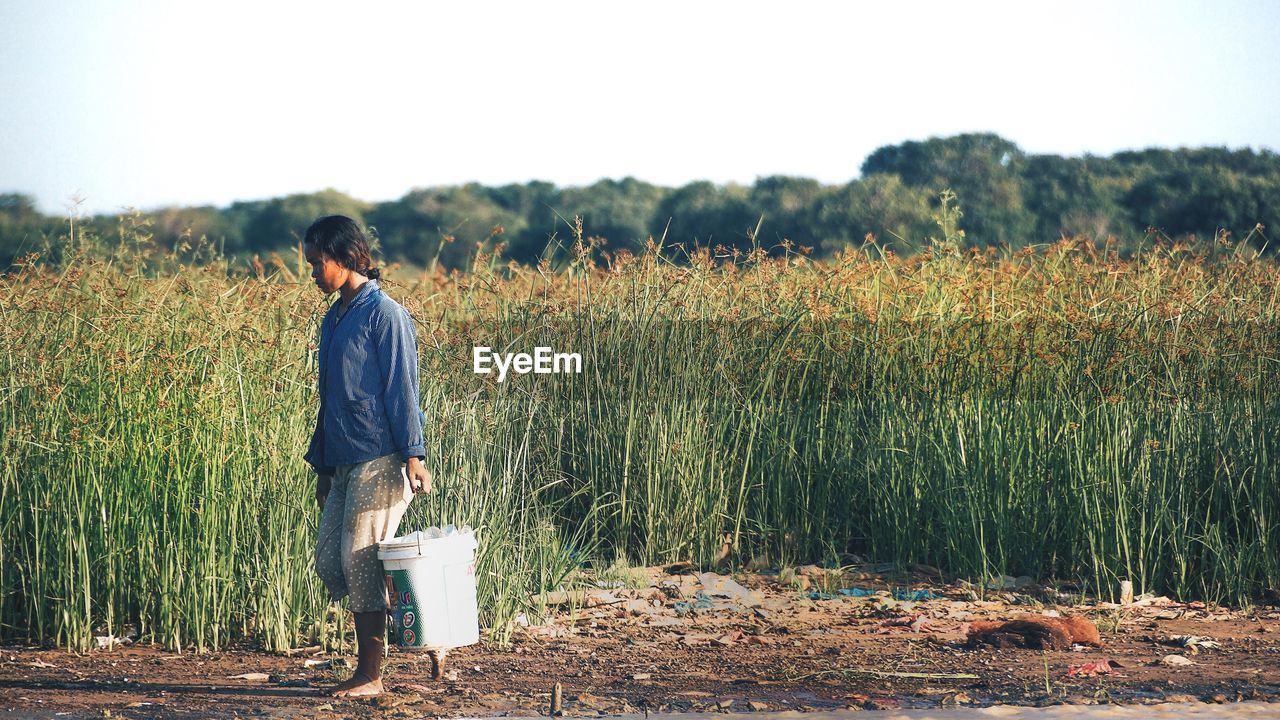 REAR VIEW OF MAN STANDING IN FIELD