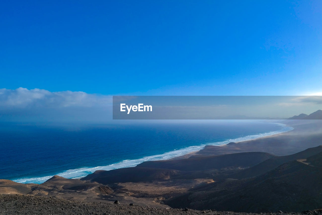 SCENIC VIEW OF BEACH AGAINST BLUE SKY