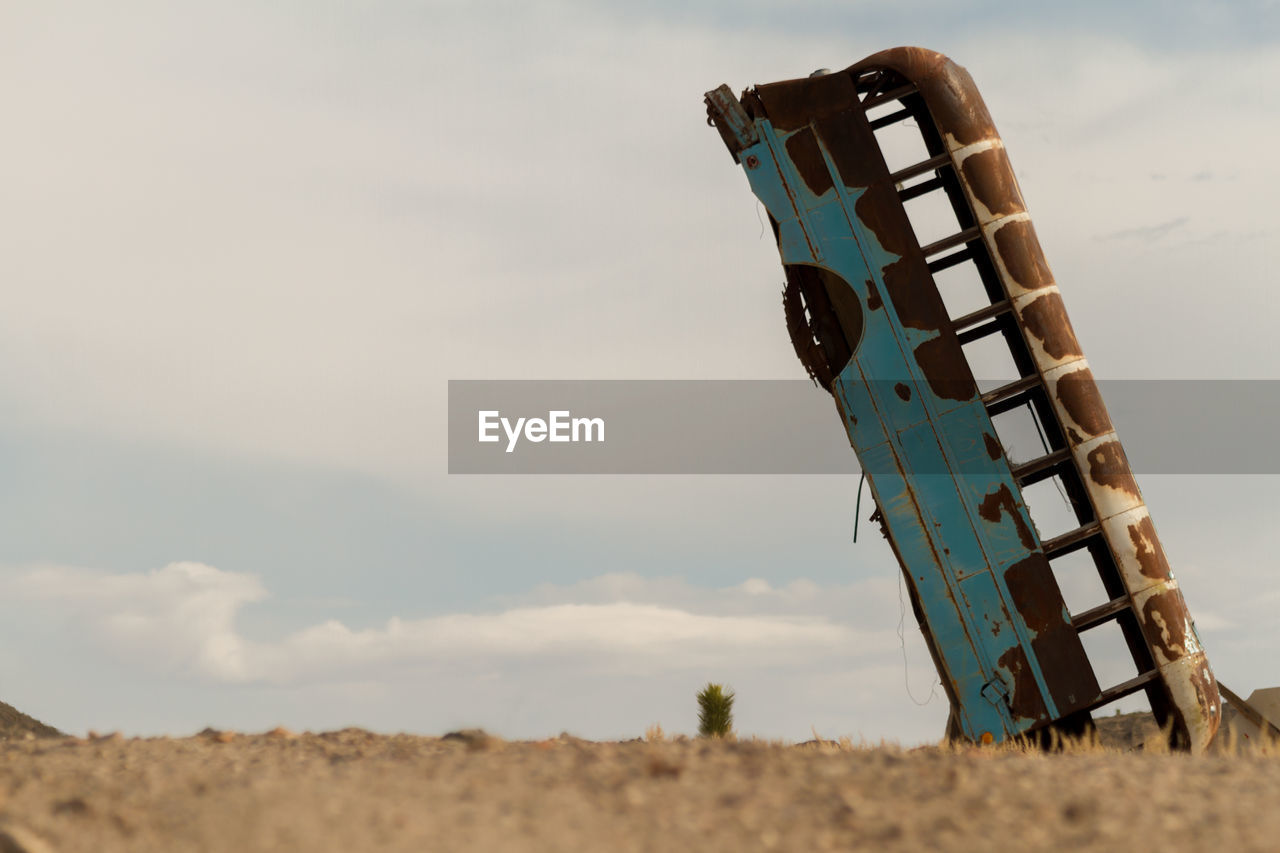 Abandoned bus on field against sky