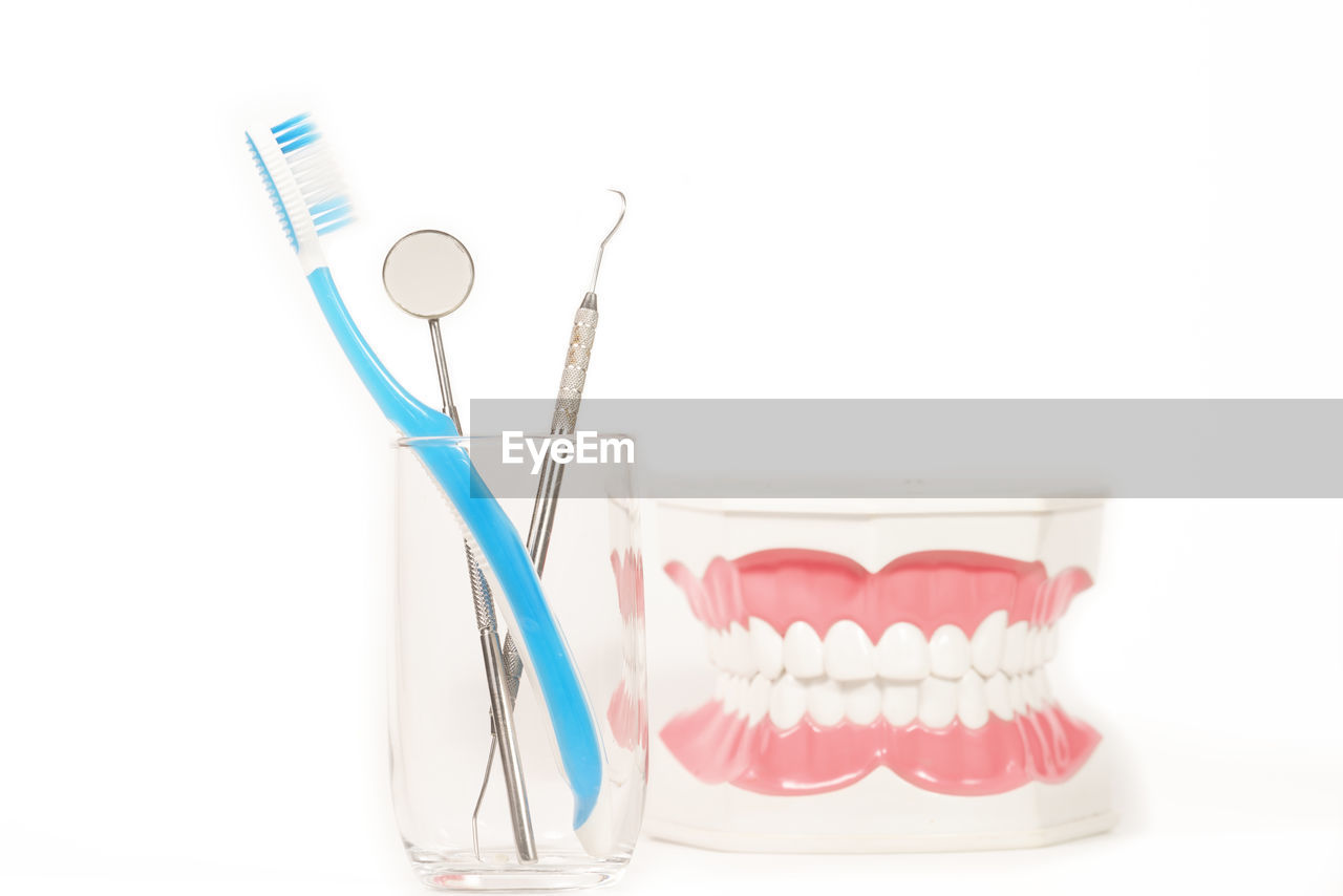 Close-up of dentures and toothbrush with medical equipment against white background