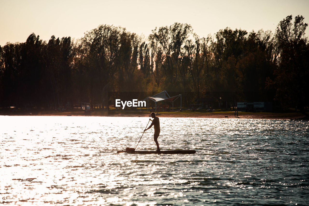 MAN STANDING ON LAKE AGAINST SKY