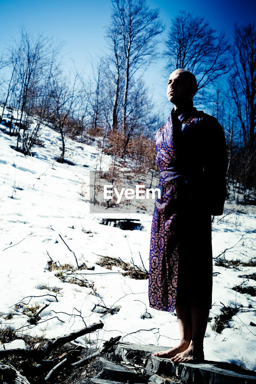 MAN STANDING ON SNOW COVERED FIELD