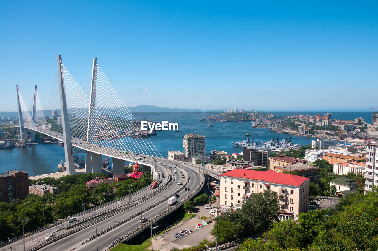 HIGH ANGLE VIEW OF BRIDGE OVER SEA AGAINST CITYSCAPE