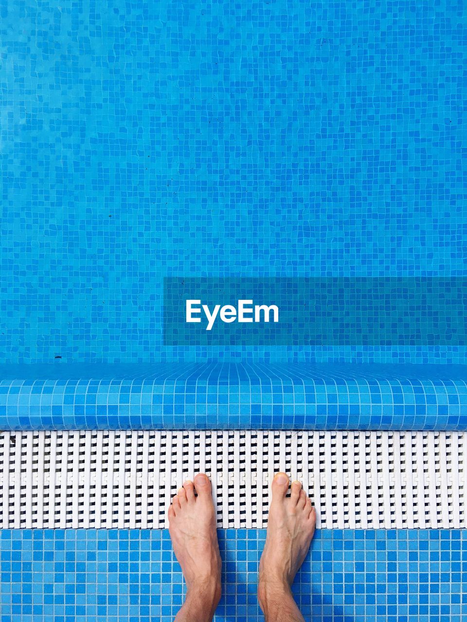 Low section of man standing at poolside