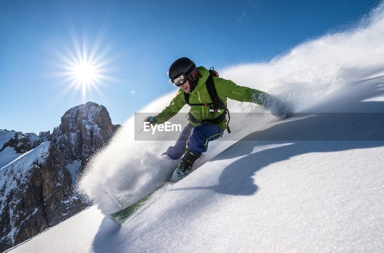 Man skiing on snowcapped mountain against sky