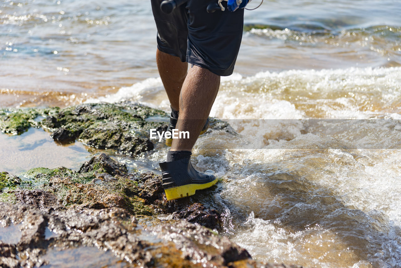 Low section of man standing in lake