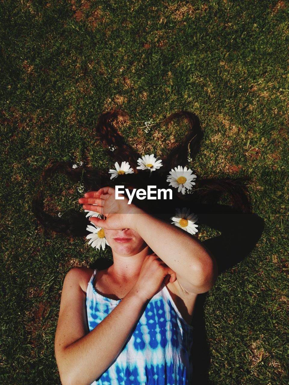 High angle view of woman with flowers on hair lying at field