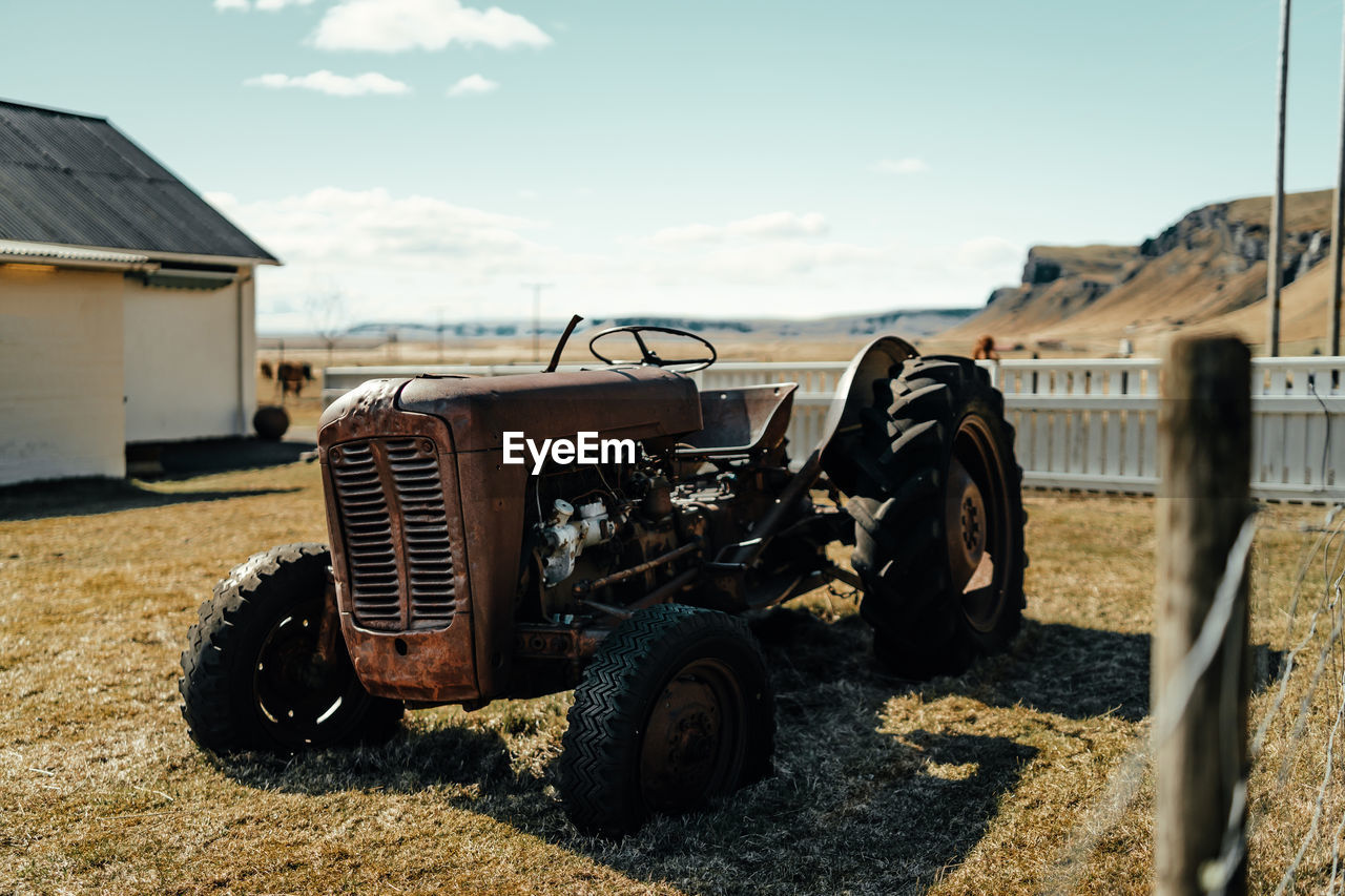 ABANDONED CAR ON FIELD AGAINST SKY