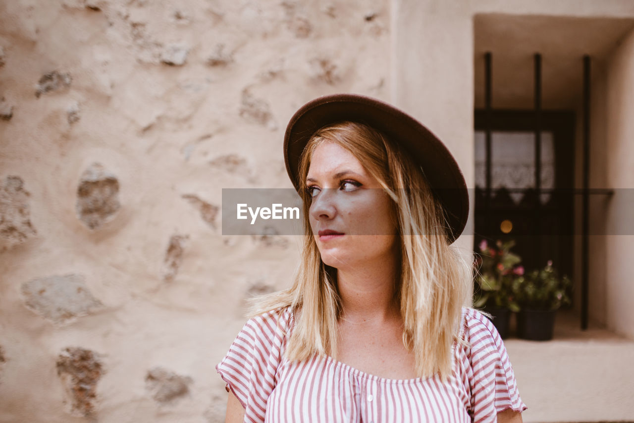 Blonde woman with her head turned sideways visiting an ancient city