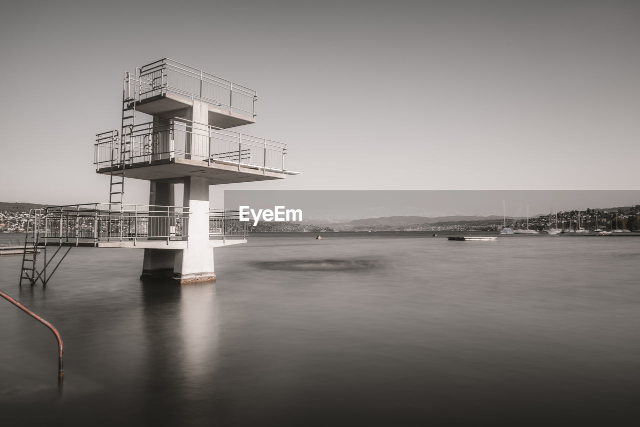 High jump tower by sea against clear sky