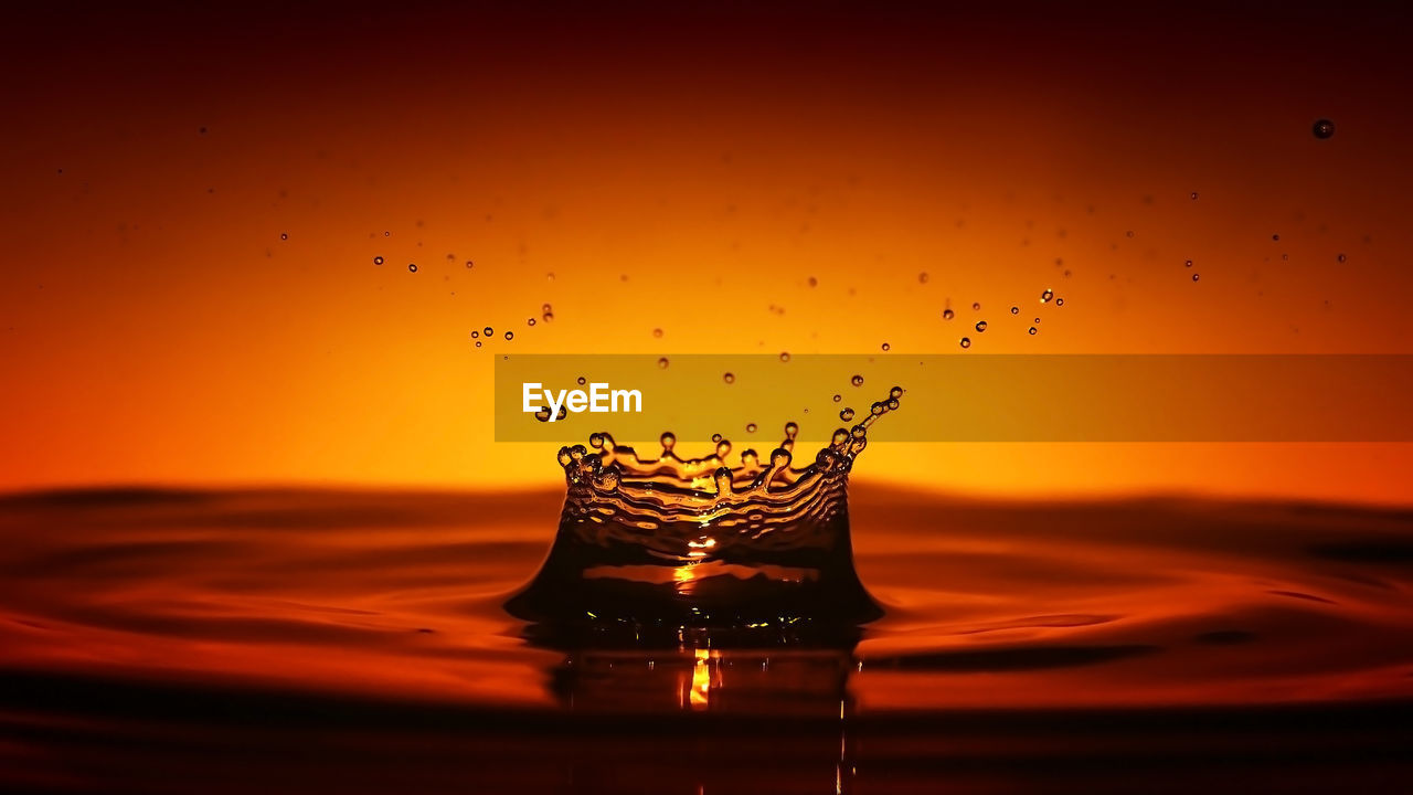 CLOSE-UP OF WATER SPLASHING AGAINST SKY DURING SUNSET