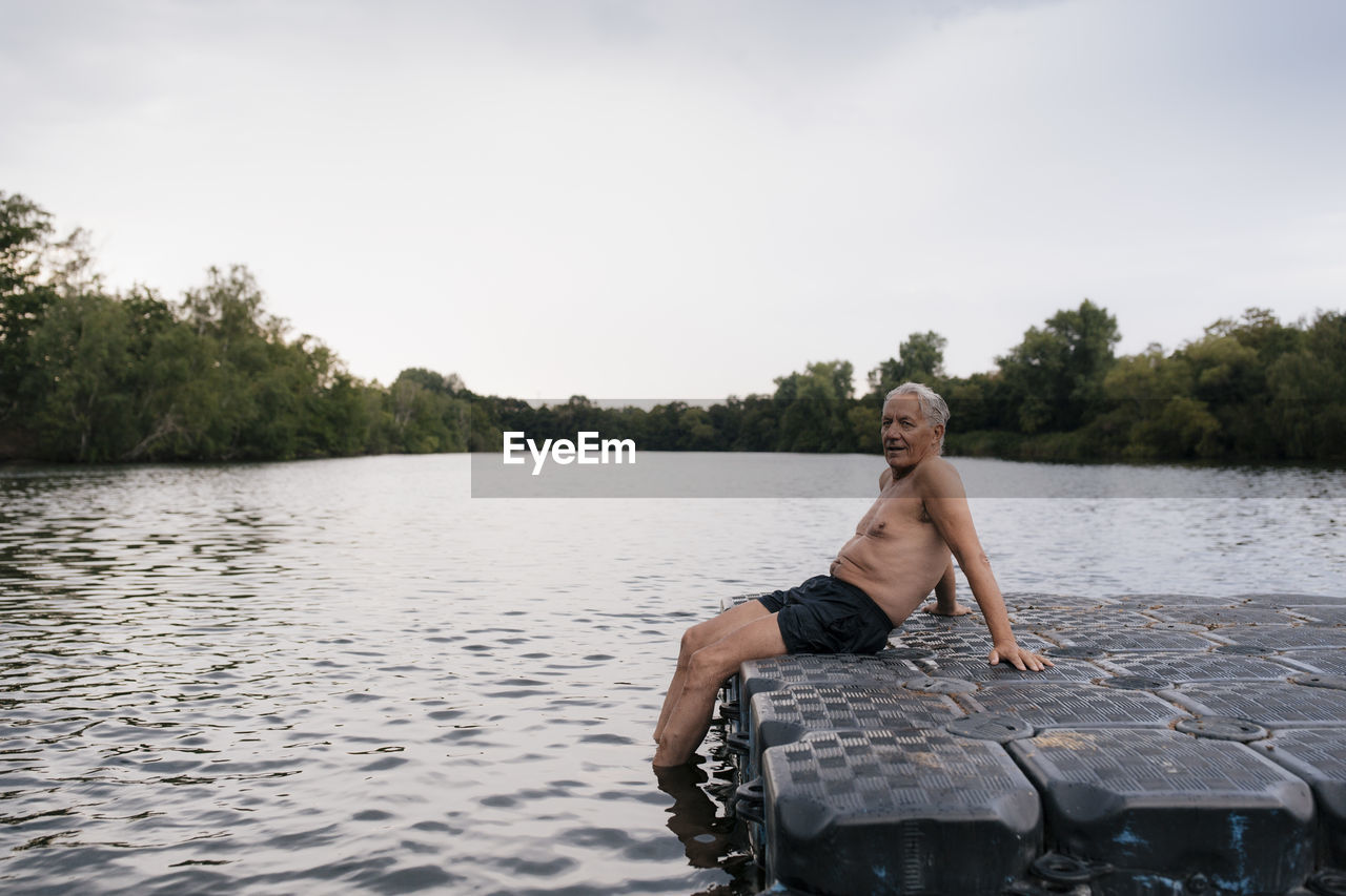 Senior man sitting on raft in a lake