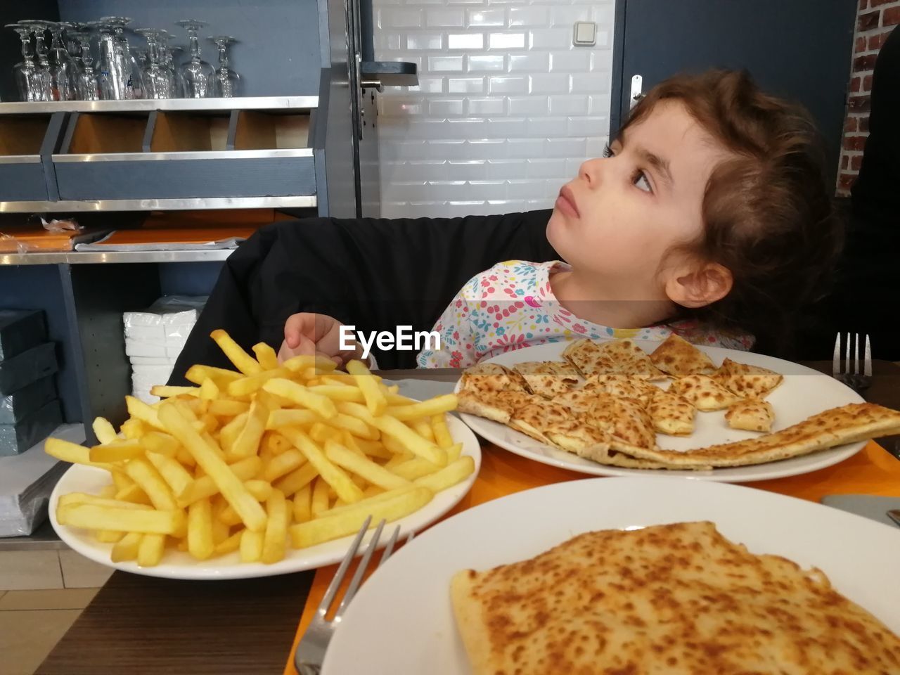 Girl looking away while having food at table
