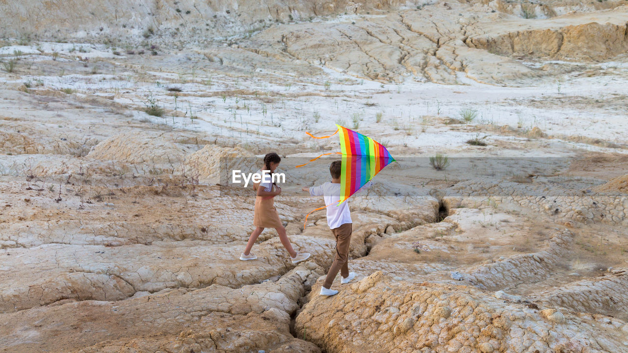 Children boy and girl with a kite their hands climb a high mountain.