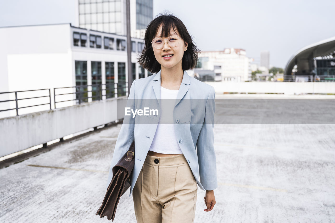 Businesswoman with briefcase walking on parking garage rooftop