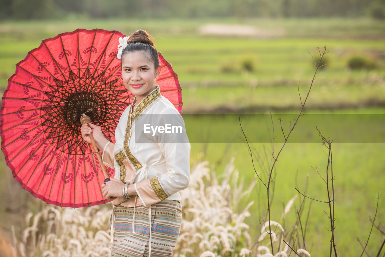 Portrait of woman with umbrella standing on field