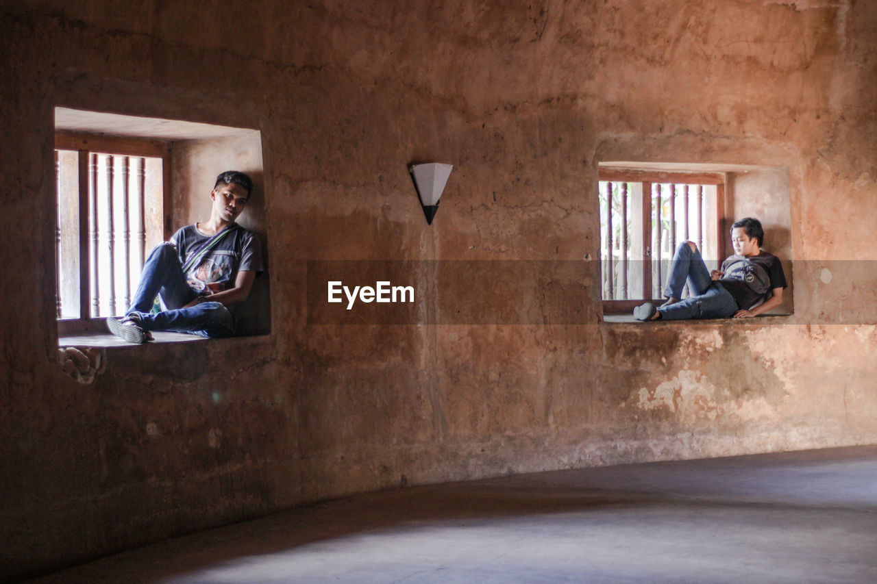 MAN SITTING IN CORRIDOR OF A HOUSE