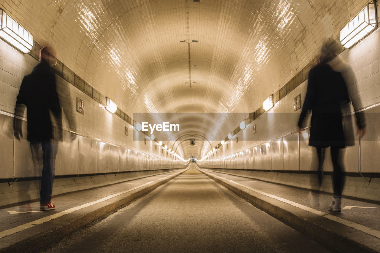 People walking in illuminated tunnel