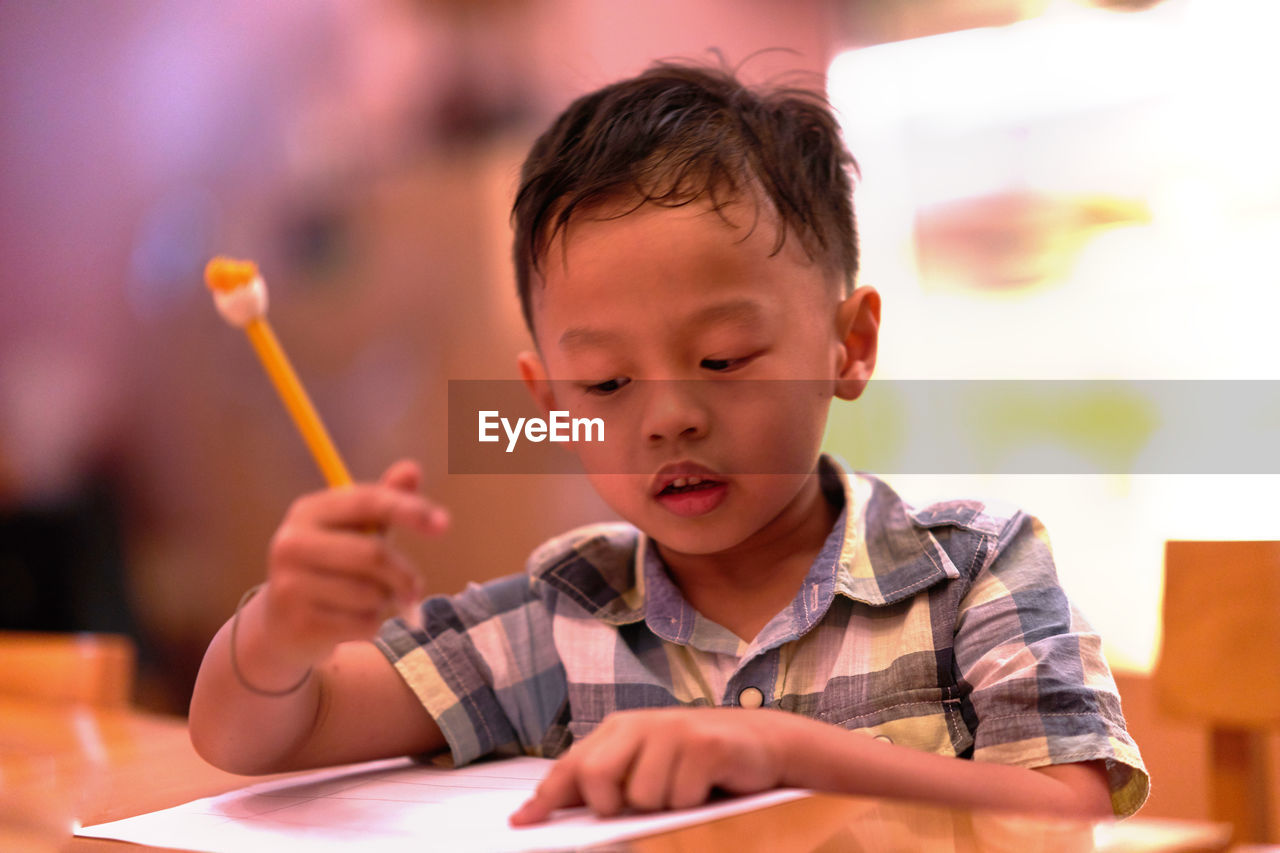 Cute boy studying on table at home