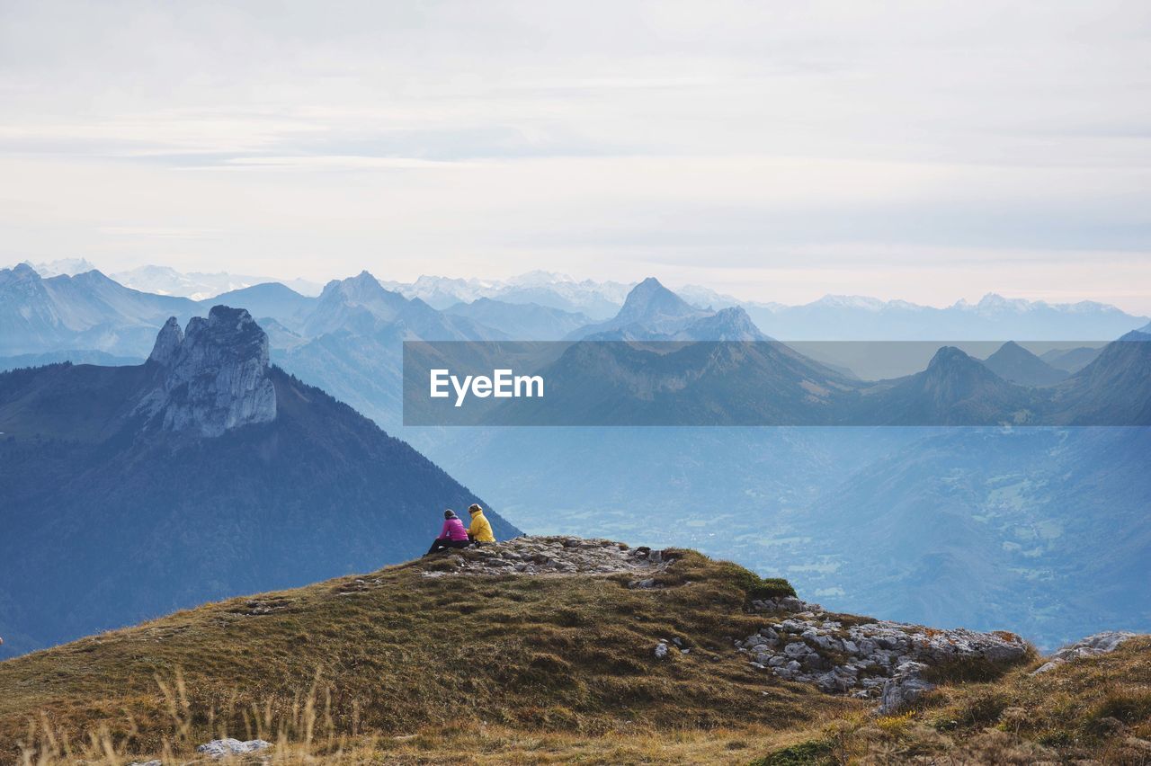 People sitting on mountain against sky