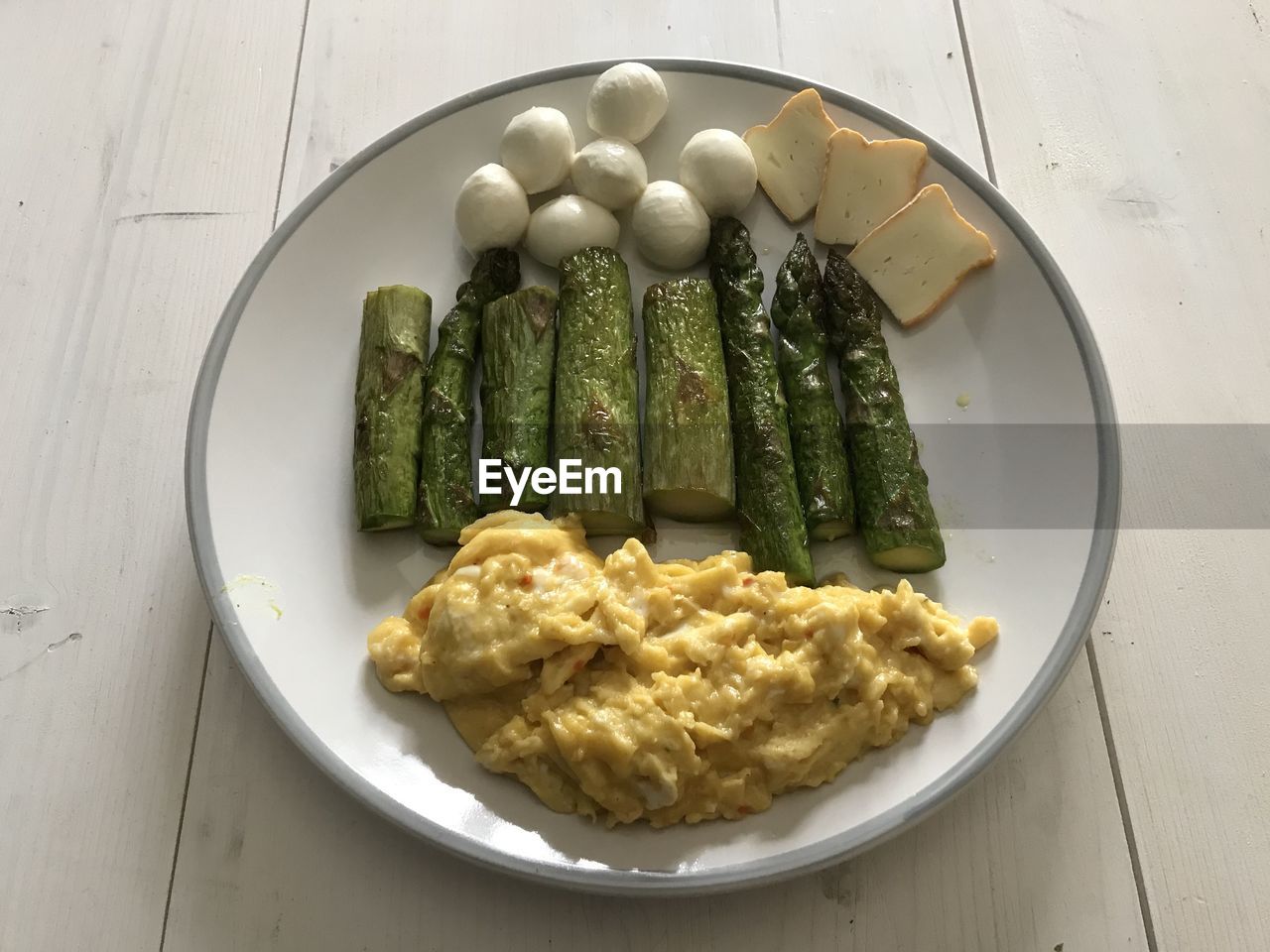 High angle view of scrambled egg and asparagus and mozzarella breakfast served on table.