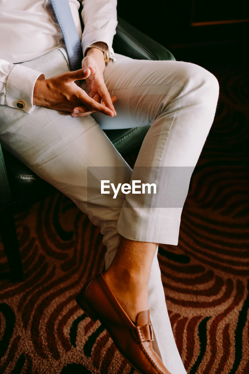 Low section of well-dressed businessman sitting on chair