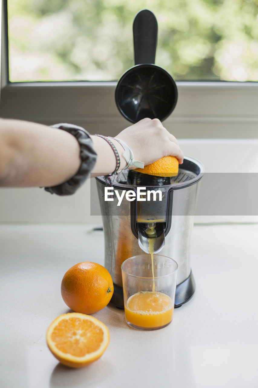 Midsection of man preparing orange juice on table