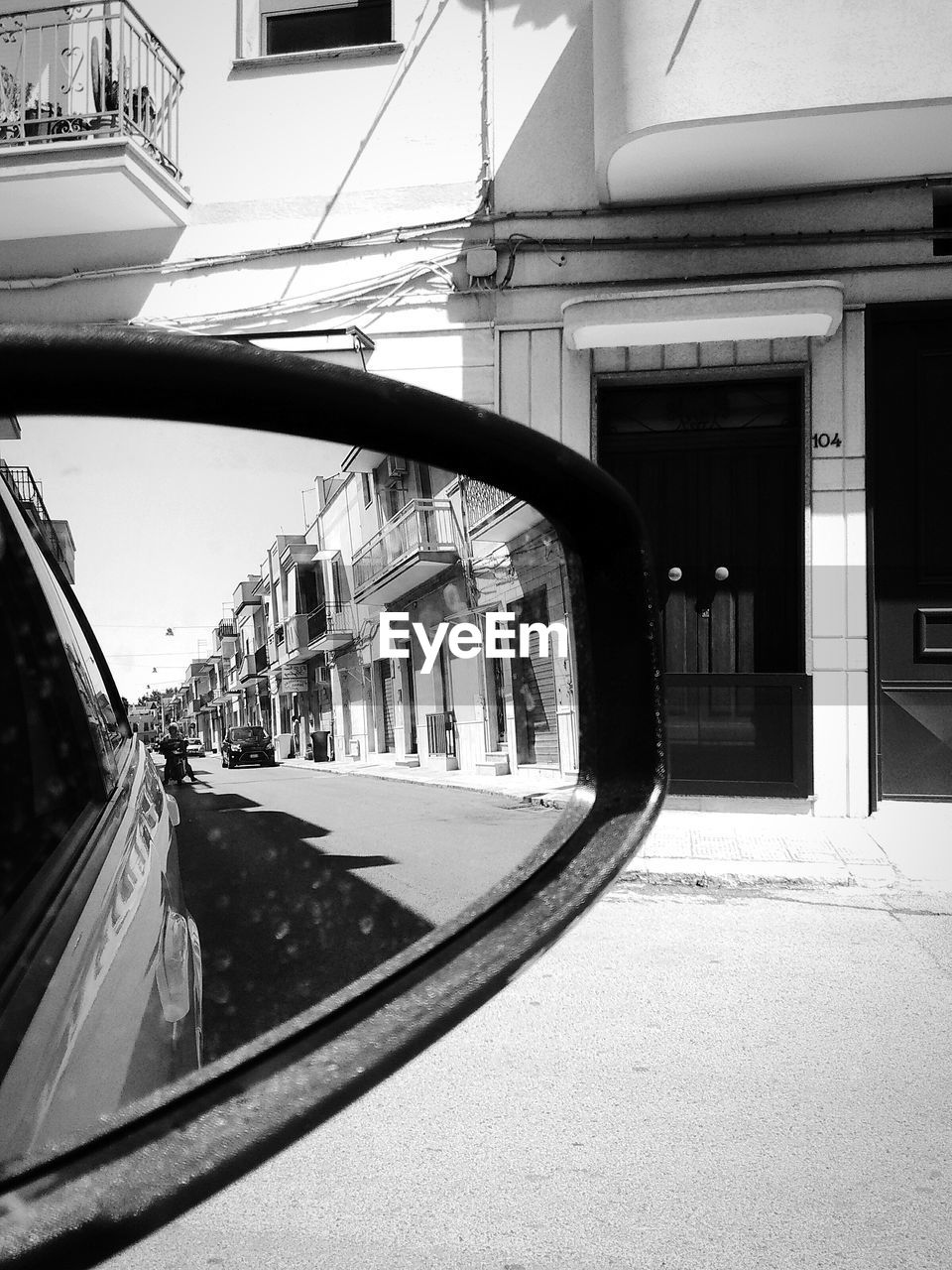 Buildings reflecting into side-view mirror of car at city