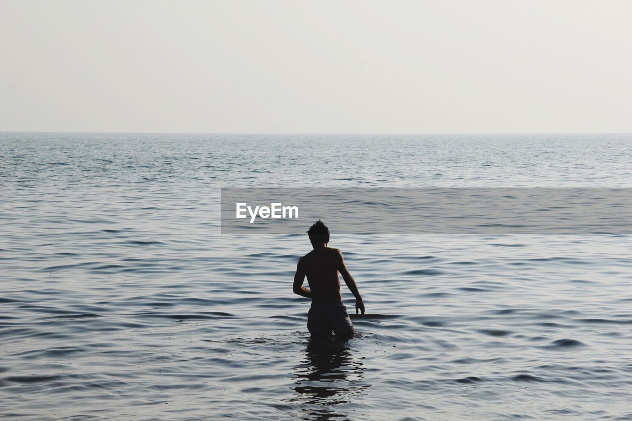 Man in sea against sky
