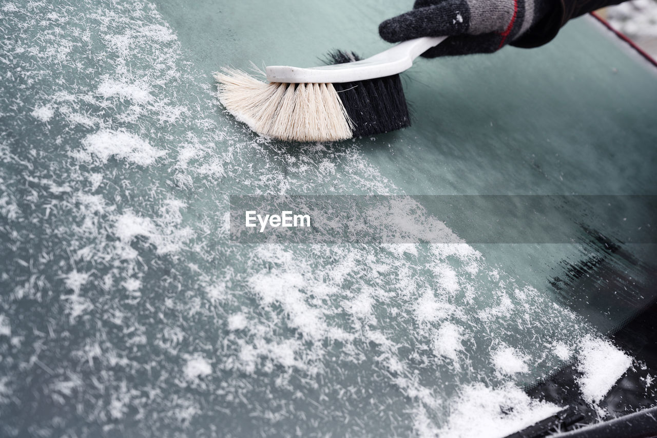 Person brushing snow on windshield