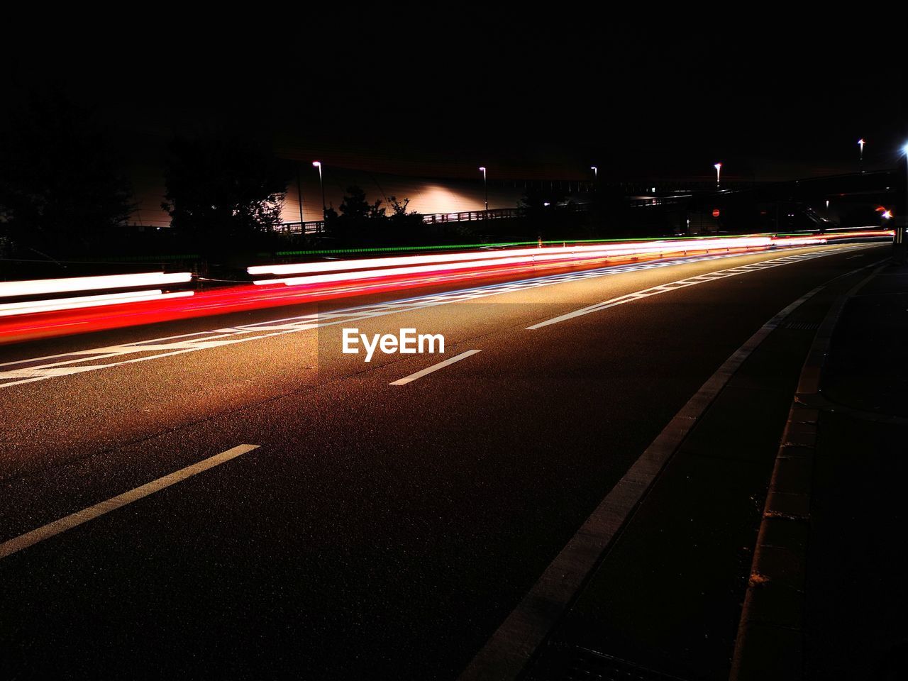 LIGHT TRAILS ON ROAD AGAINST SKY AT NIGHT