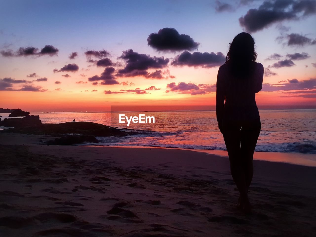 SILHOUETTE MAN STANDING ON BEACH AGAINST SUNSET SKY