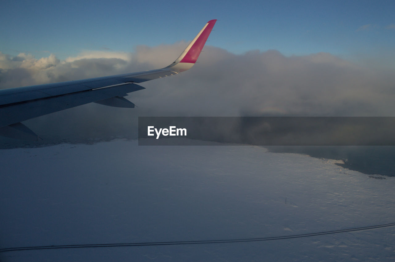 AIRPLANE FLYING IN SKY OVER MOUNTAINS