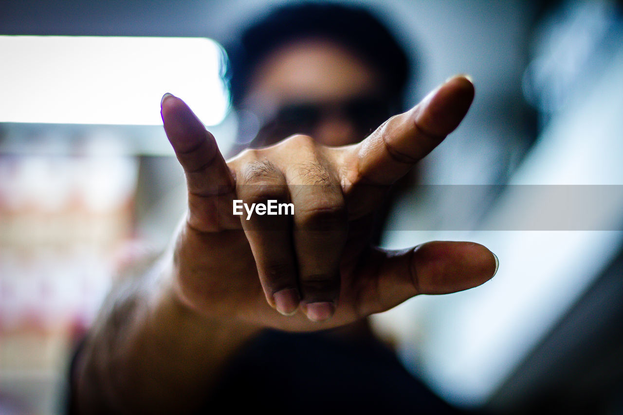 Close-up of man showing horn sign