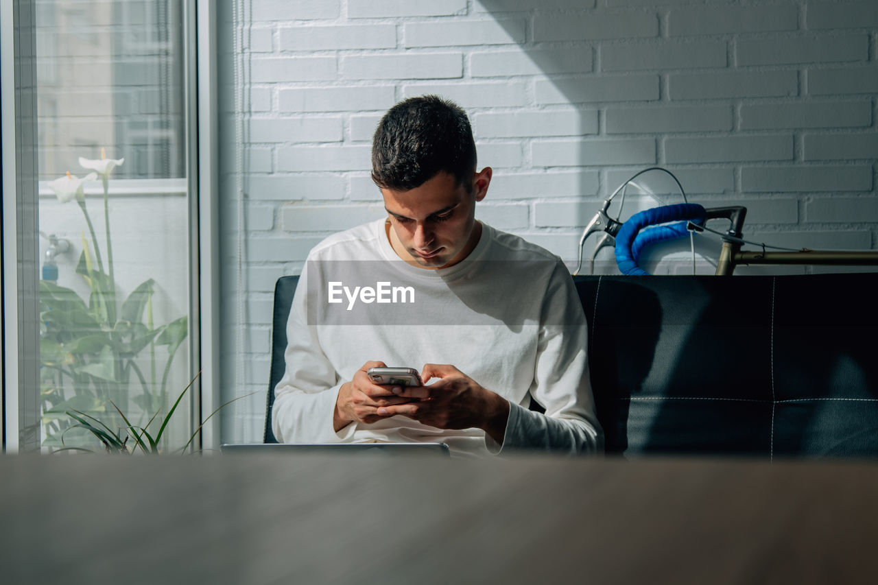 Man at home working or studying with mobile phone and computer