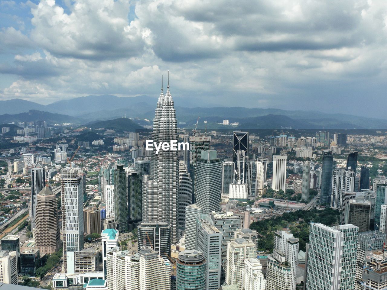 Aerial view of cityscape against cloudy sky