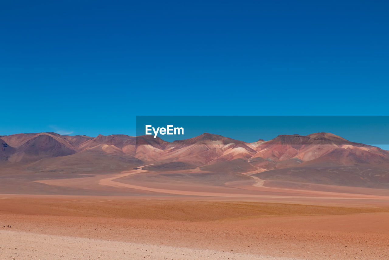 Scenic view of desert against clear blue sky