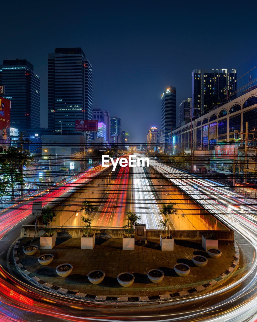 ILLUMINATED RAILROAD TRACKS AMIDST BUILDINGS IN CITY AGAINST SKY