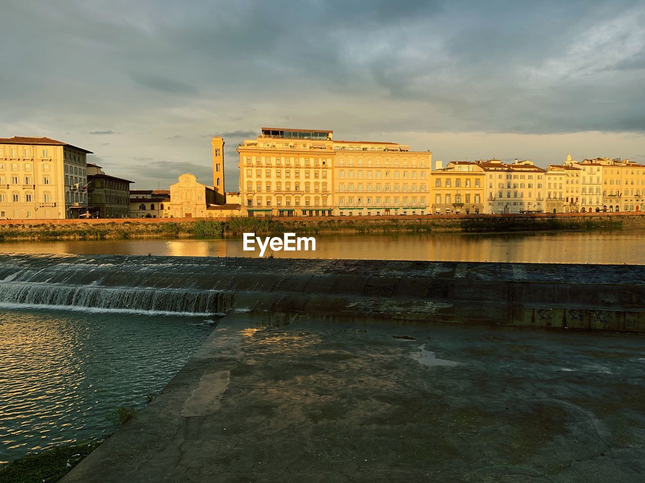 Buildings by river against sky in city