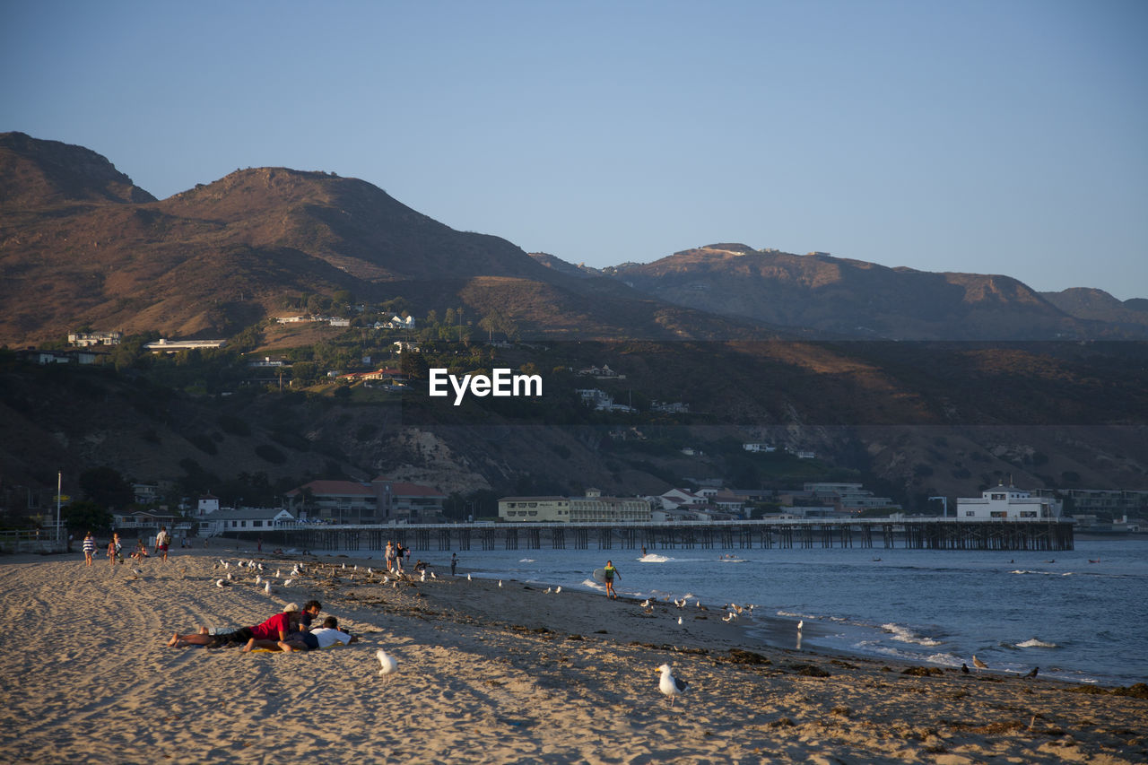 PEOPLE ON BEACH AGAINST CLEAR SKY