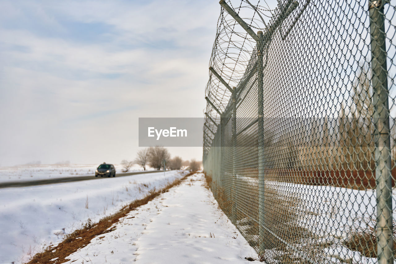 SNOW COVERED FENCE AGAINST SKY