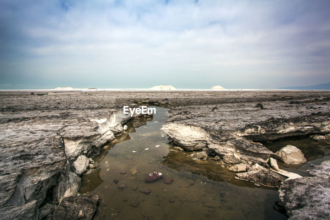 ROCKS ON SHORE AGAINST SKY