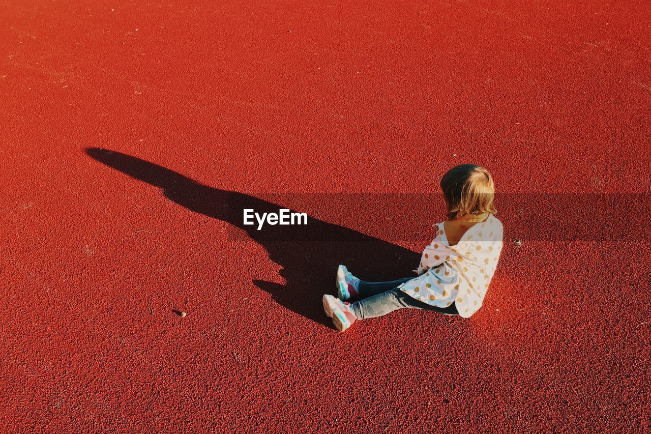 High angle view of girl relaxing on red shadow