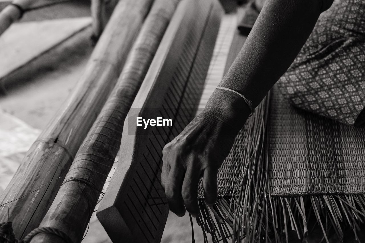 Cropped hand of woman weaving on loom